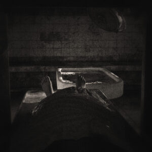 Picture of a corpse looking out from the crypt, feet out in a dilapidated morgue. Source Pixabay.com.
