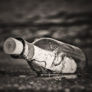 Picture of a message in a bottle washing up along the shore. Source Pixabay.com.