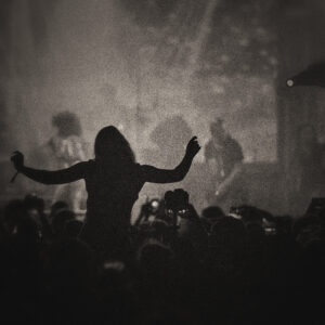 Image of an audience in a concert. One silhouette stands above the others. Image by Mike Wall from Pixabay.com.