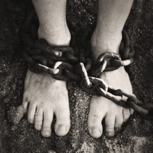Picture of a pair of feet bound by a rusty chain. Source Pixabay.com.