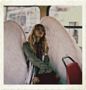 Picture of a woman sitting on a bus with eyes closed and wearing a pair of white wings. Image by Anastasiia Shevchenko from Pexels.