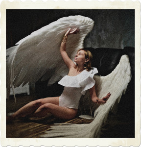 Picture of a woman wearing a white body suit, and white wings, on the ground as though using her wings as cover. Image by Victoria Model from Pixabay.