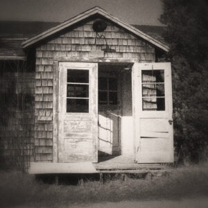 Picture of the front entrance of barracks, weather beaten and worn. Door is open, condition is poor. Source Pixabay.com.