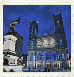 Picture of a stone cathedral glowing in blue under a blue sky. Statue faces the cathredral which is also in the shot. 