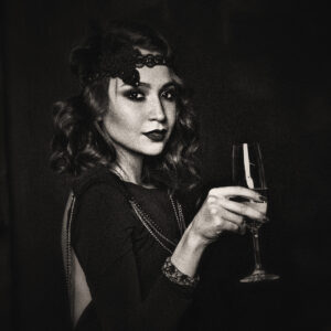 Image of a woman in Roaring Twenties fashion drinking champagne. Source Pixabay.com.