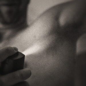 Picture of a shirtless man spraying deodorant at his armpit. Source Pixabay.com.