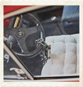 Picture of the inside of a car. The wheel has a large chain and lock attached. Image by ThinkThanks from Pixabay.