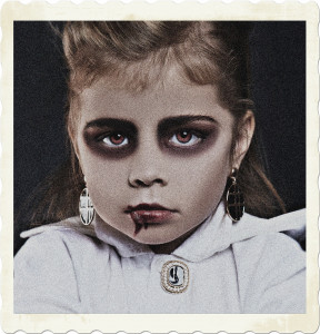Picture of a child with makup and clothing to imply she is a vampire. Including blood around the lip.