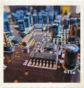 Image of a circuit board loaded with capacitors, resistors, chips, and junctions. Image by Marijn Hubert from Pixabay.