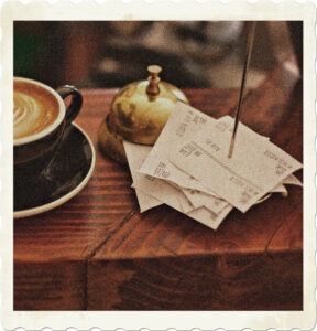 Picture of a cappuccino, bell, and a skewered receipts on a counter. Image by StockSnap from Pixabay.