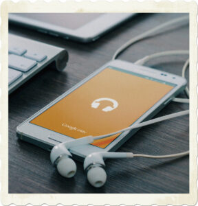 Picture of a mobile phone with headphones attached playing music. Image by Firmbee from Pixabay.