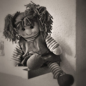 Image of a rag doll sitting on a shelf. Image by Karin Smulders from Pixabay.com.