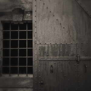 Picture of barred windows and a steel door with rivets. Original image by Cornell Frühauf from Pixabay.