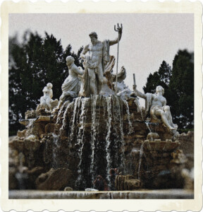 Picture of an ornate fountain, looks to be built along a grotto with baskets of goods, and several white marble statues of Greek gods on top. Image by Susanne Jutzeler from Pixabay.