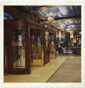 Picture of the inside of a hotel lobby, features revolving doors, chandeliers, marble floors. Image by Evelyn Chartres.