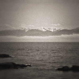 Picture taken of the water. In the distance there is mist, followed by mountains, creating the illusion that the mountains are floating. Source Pixabay.com.