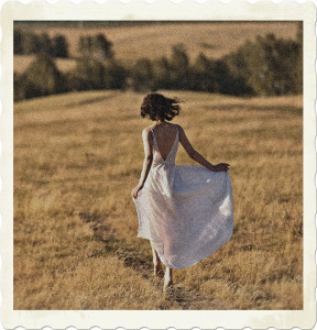 Picture of a brunette walking through a meadow with a sheer white dress on. Image by Elena Gilash from Pexels.