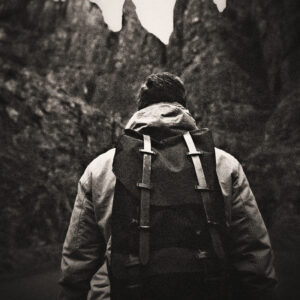 Picture of a hiker with backpack from the back, with mountains in the background. Source Pixabay.com.