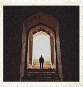 Picture of the silhouette of a woman standing under an arched stone stairwell. Light floods in from outside. Image by Aa Dil from Pexels.