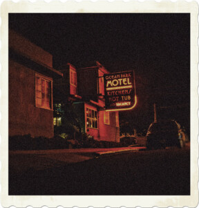 Picture focused on a motel at night, the neon sign lighting up the area.  Image by StockSnap from Pixabay.