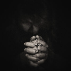 Picture of a woman with fingers interlocked while holding a rosary. Source Pixabay.com.