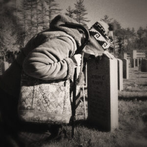 Picture of a woman leaned over her husbands tombstone. Source Pixabay.com.