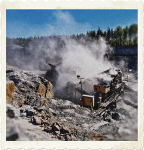 Picture of heavy equipment tearing at a rocky ridge. Smoke and fust billowing in the air. Image by Hannu Iso-Oja from Pexels.