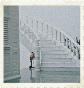 Picture of a white marble staircase, surrounded in white, with a scooter and backpack partially stashed underneath. Image by Hatice Baran from Pexels.