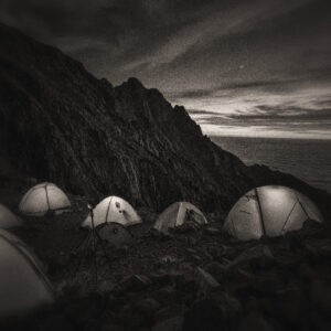 Picture of several tents lit up on a mountain top at night. Source Pixabay.com.