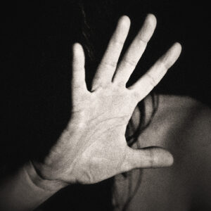Image of a woman holding out her open hand in an effort to avoid a blow. Source Pixabay.com.