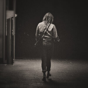 Picture of a woman walking away from the camera along a dark street. Source Pixabay.com.