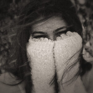 Picture of a woman out in the cold, covering her face as the wind blows. Source Pixabay.com.