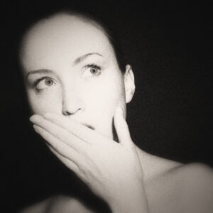Picture of a woman covering her mouth, eyes wide in shock. Source Pixabay.com.