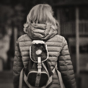 Picture of a woman wearing a coat and backpack as viewed from the back. Source Pixabay.com.