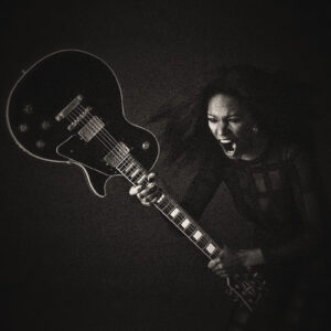 Picture of a woman screaming as she swings a guitar down to smash it. Source Pixabay.com.