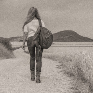 Woman walking down a dirt road with a backpack. Source Pixabay.com.