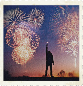 Picture of someone holding up a sparkler, while fireworks go off in the background. Image by Rakicevic Nenad from Pexels.