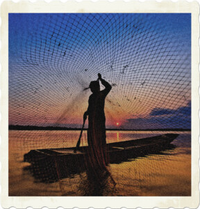 Picture of silhouette of someone on a small boat floating in the water, sun setting in the distance, casting a net towards the photographer, making it seem as though they have been caught. Image by Chanwit Whanset from Pixabay.