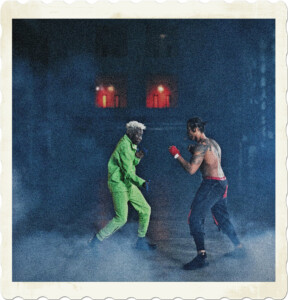 Stylised picture of two men fighting in a smoky back alley. The black man with blond hair is wearing green, while the other is shirtless, has black hair, and looks to have suspenders. The men are engaged in a flight. Image by Cottonbro from Pexels.
