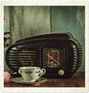 Picture of a vintage radio with a rounded shape, grills, visible face and three buttons. Ahead of it is a steaming cup of tea. Image by Lubos Houska from Pixabay.