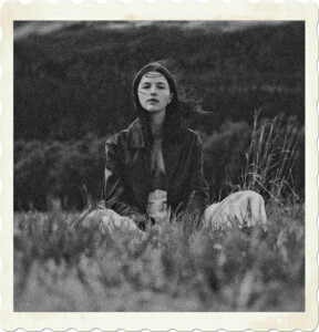 Picture of a brunette sitting in a field with hair blowing through her hair. Image by Gaspar Zaldo from Pexels.