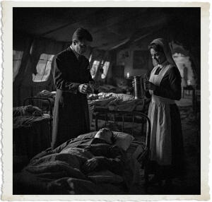Highly detailed cinematic scene set inside a dimly lit canvas ward tent at a British Casualty Clearing Station during the Great War in 1915. A distinguished British Colonel named Marc stands at the bedside of a severely wounded soldier lying in a simple cot. The Colonel is holding a glass of water that is now filled halfway, carefully helping the soldier drink. He has just used a subtle vampiric blood bond to rouse the unconscious man, who is now barely opening his eyes in response. Nearby stands a young Canadian Bluebird nurse, a brunette with lively steel-grey eyes and a mischievous grin, holding a gleaming stainless-steel pitcher. She wears the standard dark blue uniform dress with white apron and starched white veil. The nurse has just handed the pitcher over and is watching the interaction with quiet concern, commenting that they are administering sulpha but the soldier is not responding. Soft, moody lamplight casts dramatic shadows across the scene. Background shows rows of cots with other wounded soldiers, medical equipment, faint blood stains, and the muddy war-torn atmosphere visible through the tent flaps. Historical accuracy with subtle supernatural tension, realistic yet slightly stylized, intimate focus on the Colonel helping the wounded soldier drink while the nurse observes. Clothing and settings appropriate for 1915.