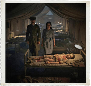 Highly detailed cinematic scene inside a dimly lit canvas ward tent at a British Casualty Clearing Station during the Great War in 1915. A distinguished British Colonel named Marc and a young Canadian Bluebird nurse Lieutenant Murphy walk together between rows of cots toward the bunk of Private Lavoie. The Colonel moves with purposeful, aristocratic grace while the nurse walks just behind him, her expression shifting from playful mischief to quiet professional concern. Private Lavoie lies asleep in his simple cot, heavily bandaged with visible spots of red blood seeping through the white dressings on his torso and limbs. A small glass vial of sedative sits on the small table beside his bed. The nurse’s steel-grey eyes show a flicker of worry as she looks at the wounded man. Soft, moody lamplight casts long dramatic shadows across the tent, highlighting rows of other wounded soldiers resting or sleeping in nearby cots, scattered medical equipment, faint blood stains, and the muddy war-torn atmosphere visible through partially open tent flaps. Historical accuracy for 1915 with subtle supernatural tension in the Colonel’s presence, realistic yet slightly stylized, intimate and poignant focus on the moment the Colonel and nurse arrive at Lavoie’s bedside.