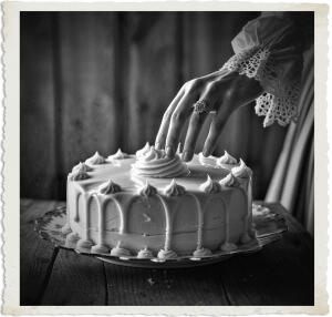 a cinematic photo of a decadent cake with rich creamy icing atop it in a delicate china dish, set against a warm wooden backdrop, a lone finger with a few wisps of lace from a sleeve visible, runs gently along the smooth icing, scooping some up, the person's hand is adorned with a vintage ring, clothing and style reminiscent of 1915 Canada, with a high-necked blouse and long skirt, the photography is shot in a warm, golden light, with a shallow depth of field, blurring the background, and emphasizing the textures of the cake, icing, and fabrics.