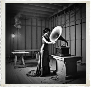 Picture of a black haired woman with green eyes wearing a slip, winding up a large phonograph sitting in the corner. Located in a ballroom under construction and mostly empty except for a few sawhorses, tables, and a large granite piece. The walls were still slats of wood running horizontally and in parallel. The workers had yet to apply plaster. Cabling protruded from openings in the walls and ceiling, none of it was connected. Several lanterns to chase away the darkness. The air was thick with smoke. Scene and clothing appropriate for 1915 Canada at night.