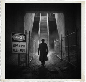 Black and white dramatic photograph of a mysterious man in a long coat and fedora walking away from the viewer toward a brightly lit concrete stairwell descending into an underground Metro station under construction. A prominent warning sign reading 'DANGER OPEN PIT KEEP OUT' stands beside the chain-link fence. The scene has a strong illusion effect: the exterior appears dark and abandoned while the interior glows with electric light, creating an eerie, atmospheric nighttime mood.