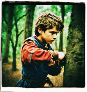 Boy of French decent, in the woods, beating on a tree in anger. His eyes narrowed, fingers formed into fists, veins bulging from neck and forehead, red faced. Clothes and scene appropriate for 1600s France.