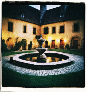 Castle courtyard at night with a well in the middle. Clothes and background appropriate for 16th century France.