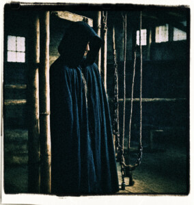 Hangman wearing a black hood at the gallows. Scene and clothes appropriate for 16th century France.