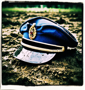 A slashed French officer' hat lays on the muddy ground. Background and clothes appropriate for 16th century France.